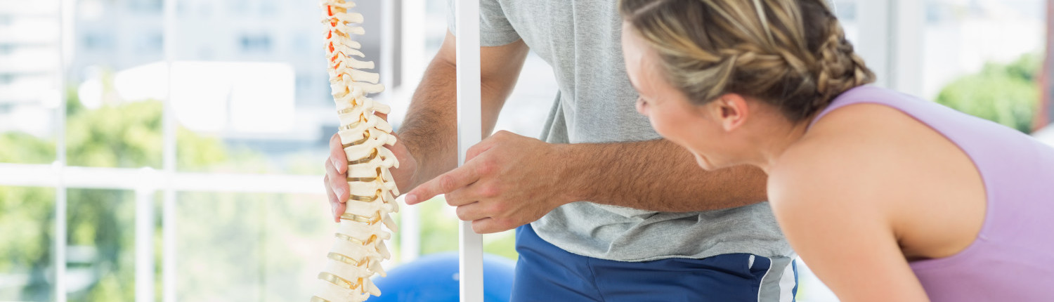 Female patient looking at chiropractic spine model. 